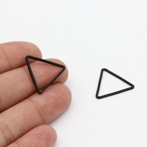 May include: Two black triangle-shaped metal hoops. The hoops are about 1 inch in diameter.
