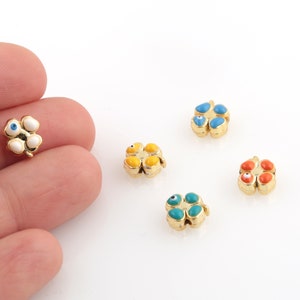 May include: Five gold-colored four-leaf clover charms with blue evil eye details. The charms are in different colors: white, yellow, blue, and orange.