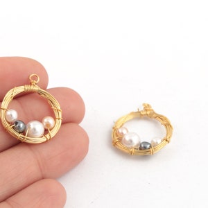 May include: Two gold wire circles with a pearl and gray bead design. The circles are about 1 inch in diameter.
