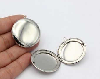 May include: Two silver locket pendants, one open and one closed. The locket is round and has a smooth, shiny surface.