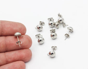Puede incluir: Un primer plano de un conjunto de pendientes de bola de plata. Los pendientes son pequeños y redondos, con un diseño sencillo. Son perfectos para el uso diario.