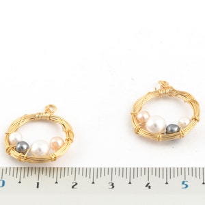 May include: Two gold wire circles with a pearl and gray bead design. The circles are approximately 2 inches in diameter.