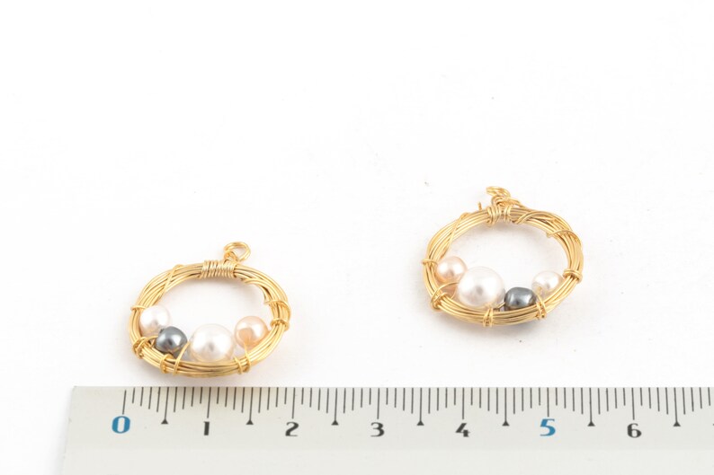 May include: Two gold wire circles with a pearl and gray bead design. The circles are approximately 2 inches in diameter.