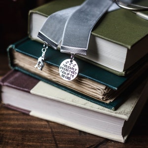 May include: A stack of three books with a grey velvet bookmark. The bookmark has two charms, one with the text "I solemnly swear that I am up to no good" and the other with a small figure.