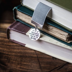 May include: A stack of three books with a silver bookmark charm that reads "I solemnly swear that I am up to no good".