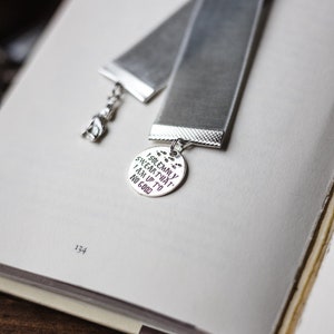 May include: A silver bookmark with a grey velvet ribbon. The bookmark features a round charm with the text "I solemnly swear that I am up to no good".