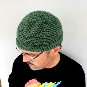 May include: A green crocheted beanie hat with a rounded crown and a turned-up brim.