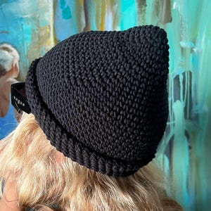 May include: A black crocheted beanie hat with a pointed crown and a folded brim.