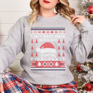 May include: Gray Christmas sweater with a red and white Santa hat and the text "Can't Make Xmas Morning! Playing Pickleball".