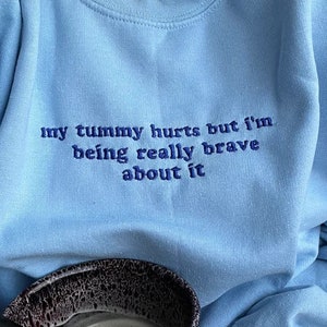 Sudadera bordada "Me duele la barriga", con frase divertida.