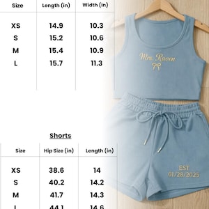 May include: Light blue two-piece lounge set with a ribbed texture. The top is a crop tank with "Mrs. Raven" embroidered in gold. The shorts have a drawstring waist and the date "01/28/2025" embroidered in gold. Size chart included.