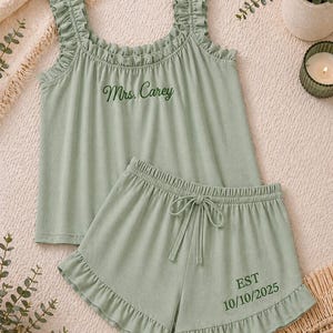 May include: Sage green pajama set with a ruffled tank top and matching shorts. The tank top has the embroidered text "Mrs. Carey". The shorts have a drawstring waist and the embroidered text "EST 10/10/2025".