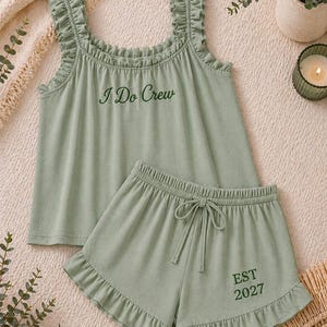 May include: Sage green pajama set with a tank top and shorts. The tank top has ruffled straps and the text "I Do Crew". The shorts have a drawstring waist and the text "EST 2027".