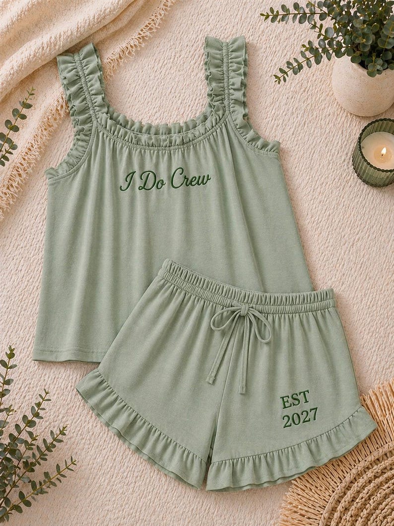 May include: Sage green pajama set with a tank top and shorts. The tank top has ruffled straps and the text "I Do Crew". The shorts have a drawstring waist and the text "EST 2027".