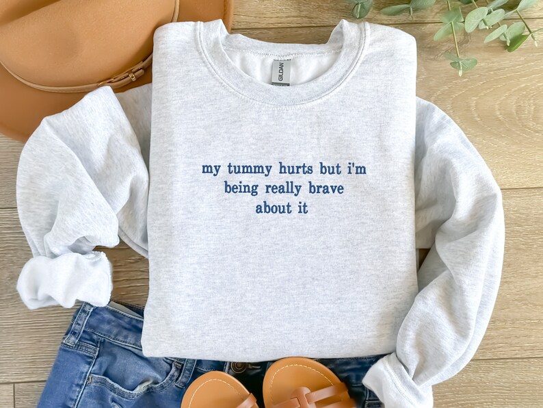 May include: Gray sweatshirt with the text "my tummy hurts but i'm being really brave about it" in blue.