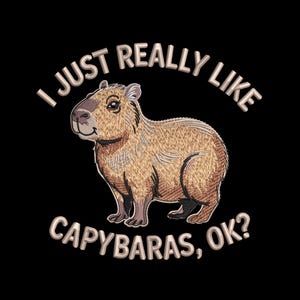 Könnte beinhalten: Gesticktes Design auf schwarzem Hintergrund mit einem Capybara und dem Text "I JUST REALLY LIKE CAPYBARAS, OK?" in Hellbraun. Das Capybara ist braun und hellbraun mit einem lächelnden Gesichtsausdruck.