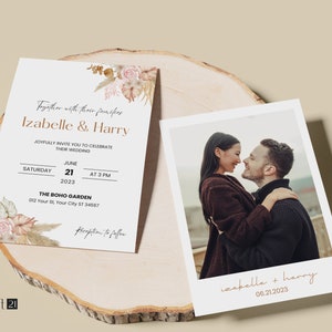 May include: Wedding invitation and photo card set. The invitation features the names "Izabelle & Harry" with floral accents and event details. The photo card shows a couple embracing. Both are on a wooden surface.