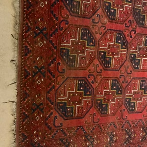 K&ouml;nnte beinhalten: Ein roter, blauer und goldfarbener Teppich mit geometrischem Muster. Der Teppich hat einen Fransenrand und ist aus Wolle.