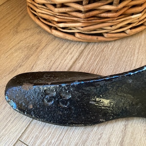 May include: A black metal shoe last with the number "25" stamped on the side. The last is a tool used by shoemakers to shape and form shoes.