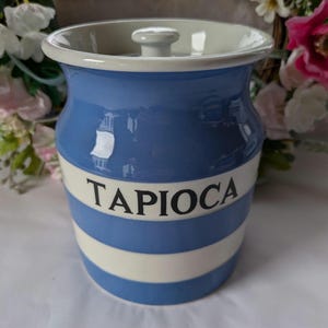 May include: A blue and white striped ceramic canister with a lid and the word "TAPIOCA" printed on the front.