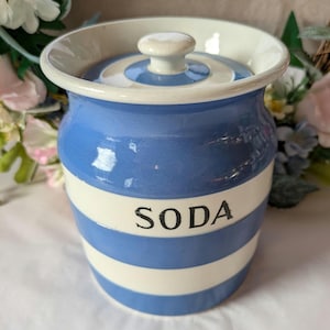 May include: A blue and white striped ceramic jar with a lid. The jar has the word "SODA" printed on the front.