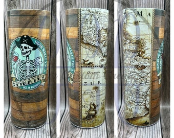 May include: A stainless steel tumbler with a wood grain design and a pirate skull graphic. The graphic says "Drinking before noon makes you a pirate, not an alcoholic". The other side of the tumbler features a vintage map with the words "Oceanus Zur" and "Tropics Peruvian".