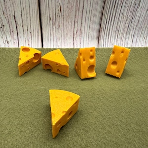 May include: Five triangular wedges of yellow cheese with holes are arranged on a green surface. The cheese wedges are in various positions, with some standing upright and others lying flat. The background is a wooden panel.