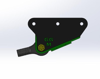 May include: A black metal bracket with green and gold accents. The bracket has three holes and a textured extension. The letters "GG M" are visible in green. A gold-colored bolt is also visible.