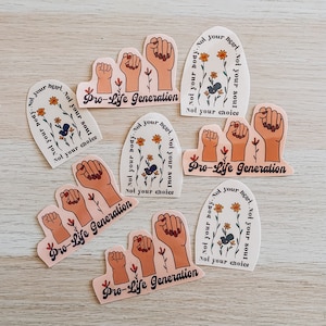 Puede incluir: Una colección de pegatinas con varios diseños. Algunas pegatinas presentan puños en alto y el texto "Pro-Life Generation". Otras pegatinas tienen diseños florales y las frases "Not your body, not your heart, not your soul, not your choice."