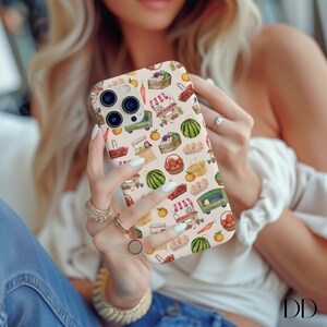 May include: A phone case with a repeating pattern of farmers market elements, including watermelon, oranges, baskets of produce, and market carts. The case has a light beige background and a glossy finish. The case is designed for a smartphone.