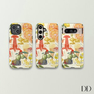 Pode incluir: Tr&ecirc;s capas de telefone com um design colorido que apresenta lim&otilde;es, laranjas, lagostas, azeitonas e outros alimentos italianos. As capas s&atilde;o brancas com um fundo amarelo.