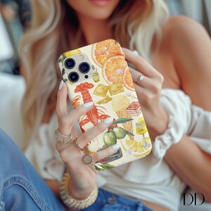 Pode incluir: Uma capa branca para iPhone com uma ilustra&ccedil;&atilde;o colorida de comida e bebidas. O design inclui uma lagosta, lim&otilde;es, massa e um copo de limonada.