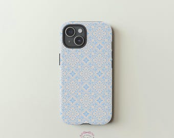 Op de afbeelding: Een telefoonhoesje met een lichtblauw en beige bloemenpatroon. De hoes heeft een herhalend ontwerp van gestileerde bloemen en bladeren. Het heeft een camera-uitsparing en zijknoppen.
