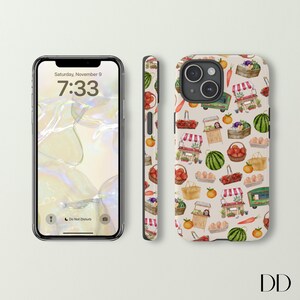 May include: A smartphone and phone case featuring a repeating pattern of a farmer's market. The pattern includes illustrations of produce, market stalls, baskets, and a green truck. The phone screen displays the time as 7:33 and the date as Saturday, November 9.