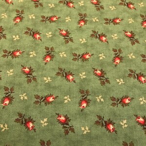 May include: Green fabric with a repeating pattern of small red roses with brown stems and leaves.