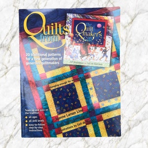May include: Book cover with a colorful quilt design and the title "Quilts from" in yellow letters. The subtitle is "20 traditional patterns for a new generation of generous quiltmakers". The book is by Joanne Larsen Line and Nancy Loving Tubesing. The cover also features a smaller image of a book titled "The Quiltmaker's Gift" by Jeff Brumbeau and Gail de Marcken.