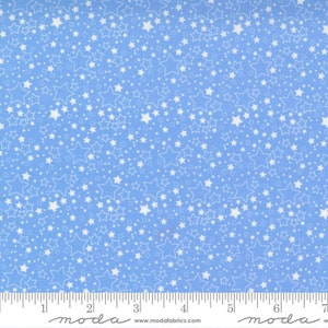 May include: Pale blue fabric featuring a repeating pattern of white stars in different sizes. The stars are outlined and filled, creating a celestial design. A ruler is visible along the bottom edge.