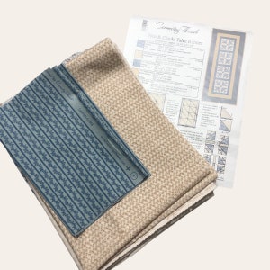 Peut inclure: Un ensemble de tissus avec un patron de couture pour un chemin de table. Les tissus comprennent un tissu à rayures bleues et blanches, un tissu beige à motifs et un tissu crème. Le patron s'intitule "Hen & Chicks Table Runner".