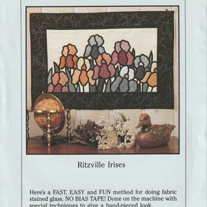 May include: A quilt pattern featuring a stained glass design of irises in shades of pink, purple, blue, and green. The pattern is titled "Ritzville Irises" and includes instructions for a fast, easy, and fun method for doing fabric stained glass. The pattern is from Spectral Designs and is copyright 1992.