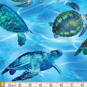 May include: A blue and green sea turtle pattern on a blue background. The pattern is repeated throughout the fabric. The fabric is measured with a ruler in inches.