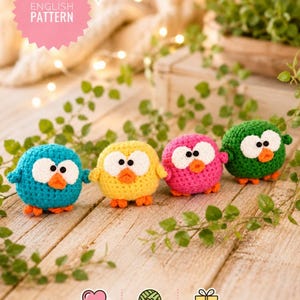 Può includere: Quattro figurine di gufo all'uncinetto dai colori vivaci: blu, giallo, rosa e verde, ognuna con occhi bianchi e becchi e zampe arancioni. I gufi sono su una superficie di legno con fogliame verde. Include il testo "ENGLISH PATTERN".