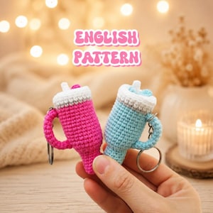 Pode incluir: Dois chaveiros de bebida de crochê feitos à mão, um rosa e outro azul, com detalhes brancos e cinzentos. Cada chaveiro tem uma alça e um anel prateado. O texto "ENGLISH PATTERN" é exibido acima.