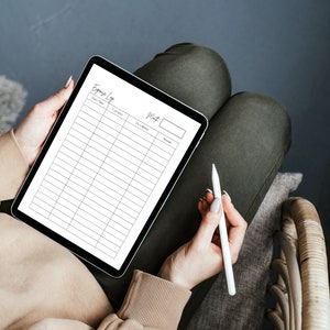 Op de afbeelding: Een witte tablet met een lege spreadsheet voor een uitgavenlogboek op het scherm. De tablet wordt vastgehouden door een persoon met een witte stylus in hun hand.