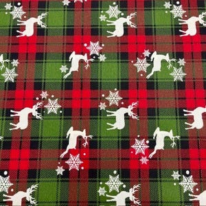 May include: Red and green plaid fabric with a white silhouette of a reindeer and snowflakes. The fabric is perfect for crafting projects like pillows, blankets, and bags.