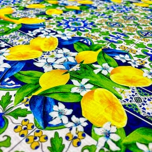 May include: A white fabric with a blue and green pattern of lemons, leaves, and flowers. The pattern is reminiscent of Italian majolica tiles.