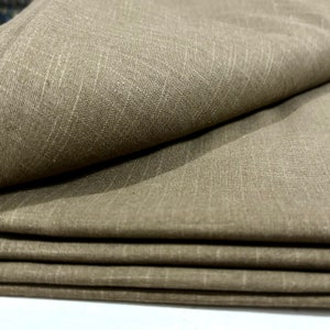 May include: Close-up of a folded piece of brown fabric with a textured weave. The fabric has a subtle sheen and a slightly rough texture.