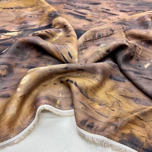 May include: A brown and beige fabric with a woodgrain pattern. The fabric is soft and has a subtle sheen.