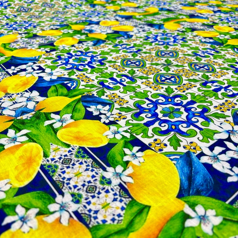 May include: A blue and white patterned fabric with yellow lemons and green leaves. The pattern is reminiscent of Italian tiles.