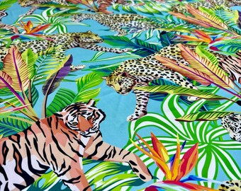 May include: A blue fabric with a repeating pattern of tigers and leopards in a jungle setting. The animals are depicted in a colorful, stylized design with green, yellow, orange, and red accents.