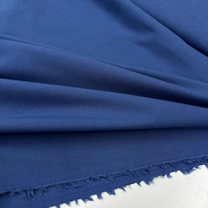 Könnte beinhalten: Nahaufnahme eines tiefblauen Stoffes mit einer rohen Kante. Der Stoff hat eine glatte, gleichmäßige Textur.